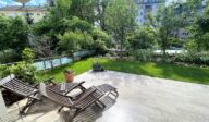 Private Gartenterrasse des Apartmenthauses Christina in Nürnberg mit zwei Holzliegestühlen, gepflegtem Rasen und Blick ins begrünte Wohnviertel – ruhiger Rückzugsort mitten in der Stadt, nahe dem Design Hotel Vosteen. / Private garden terrace of Apartmenthaus Christina in Nuremberg featuring two wooden sun loungers, well-kept lawn and view of the leafy residential area – peaceful retreat in the city center near Design Hotel Vosteen.